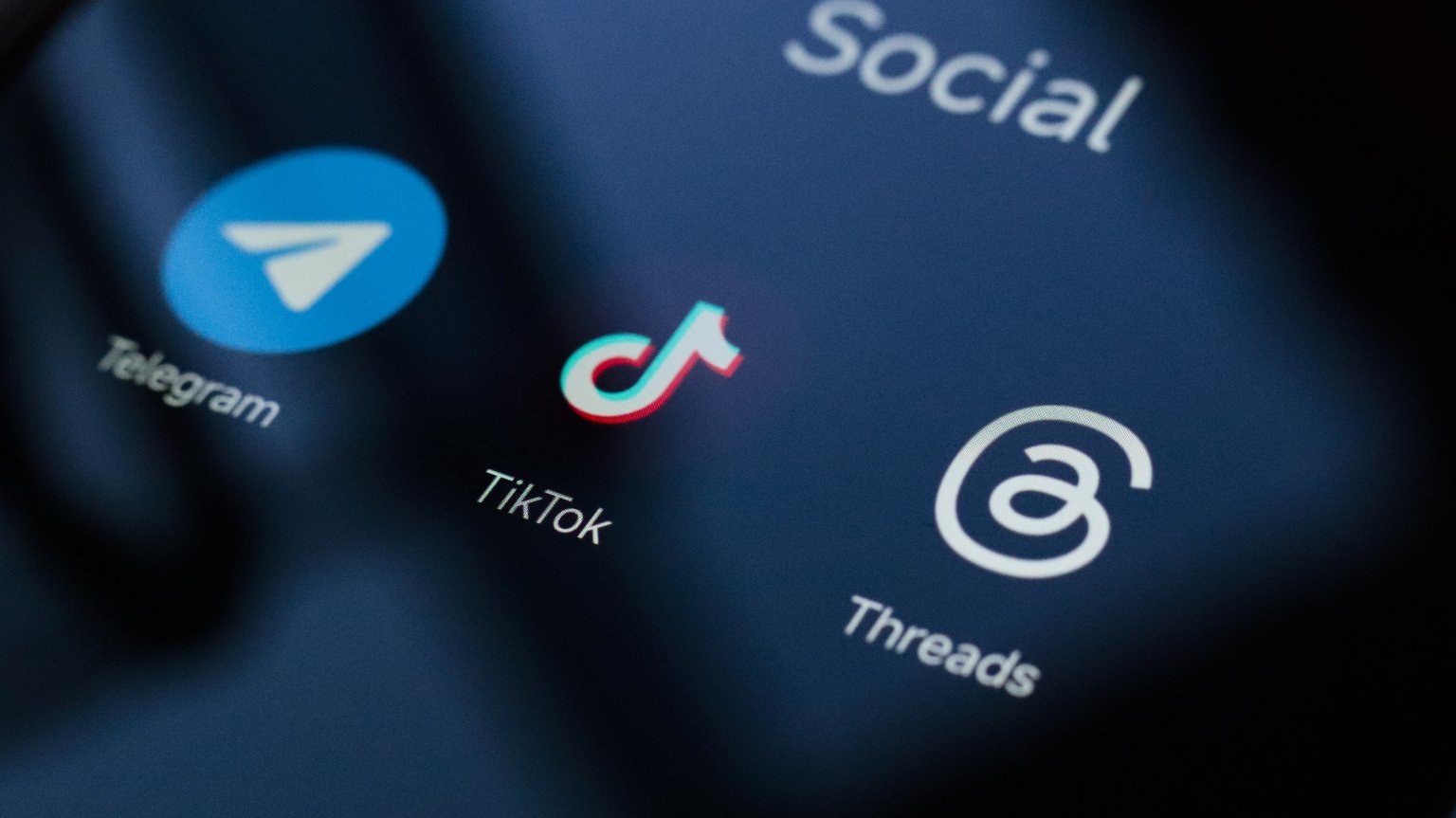 A close up of a phone screen showing the Telegram, TikTok, and Threads apps. 