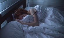 Person in bed holding blankets, asleep