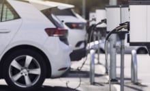 A row of electric vehicles plugged in at a charging station