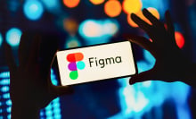 A pair of hands holding a phone with the Figma logo.