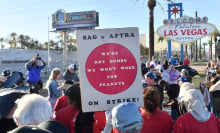 SAG-AFTRA and WGA workers gather in Las Vegas. A person holds a sign that reads, "We're not Dumbo. We won't work for peanuts."