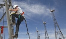 A person climbs down the ladder of a tall wind turbine.