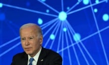 Joe Biden sits in front of an abstract blue backdrop. 