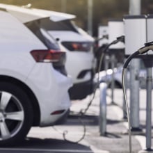 A row of electric vehicles plugged in at a charging station