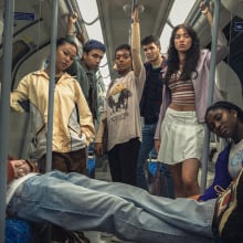 A group of teens stand for a posed photo in a London underground train.