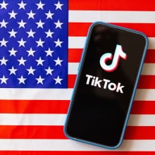 TIkTok logo on mobile phone with the American flag in the background.