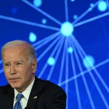 Joe Biden sits in front of an abstract blue backdrop. 