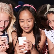 A group of three young girls using smartphones.