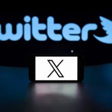 X logo on mobile device in front of the old Twitter logo