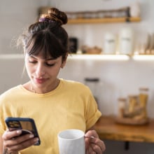 A woman looks at her phone in the kitchen.