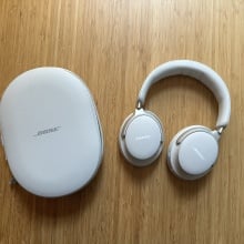 A pair of Bose QuietComfort Ultra headphones with case on wood surface