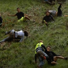 People falling down a steep hill are frozen in various stages of tumbling over.