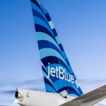 Plane with JetBlue logo on tail flying through sky