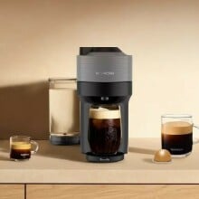 the nespresso vertuo pop+ machine sits on a counter with several coffee cups around the machine and one nespresso vertuo pod