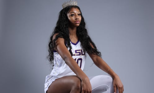 Angel Reese sits for a portrait while wearing white and purple LSU jersey and a crown 