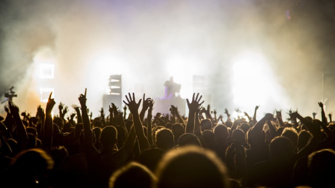 Hundreds of people with their arms in the air at a music festival