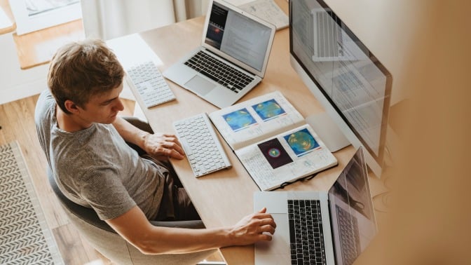 Man sat at desk with papers and laptop