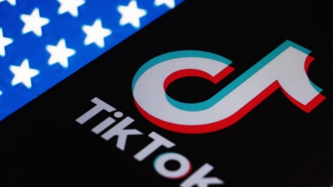 A phone displaying the TikTok logo on an American flag backdrop.