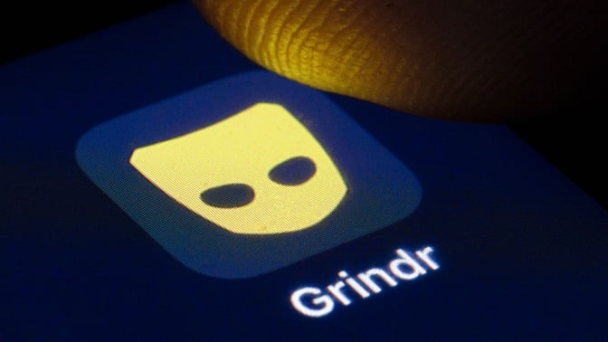 someone tapping grindr on a phone