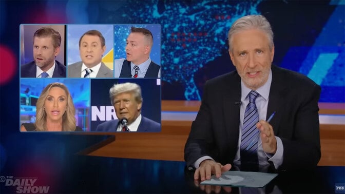 A man sits behind a talk show desk. In the top-left is a collage of images of people on the news.