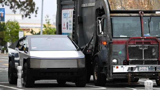 A Cybertruck parked next to a garbage truck