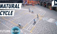 A top down view of children riding bicycles over the painted art installation "Natural Cycle".