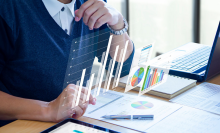 man sitting at desk looking at papers and graphs