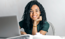 Woman smiling at a desk with her laptop