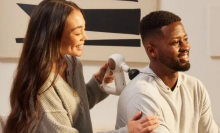 Woman massaging man's back with therabody device