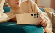 a close-up of a woman holding a samsung galaxy s24 ultra while laying on a couch