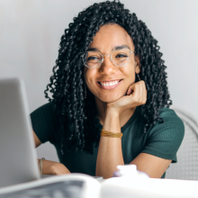 Woman smiling at a desk with her laptop