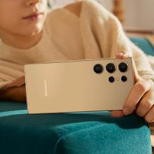 a close-up of a woman holding a samsung galaxy s24 ultra while laying on a couch