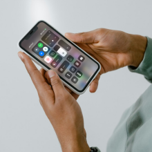 A mockup of an iPhone screen's Control Centre on an iPhone held by a person.