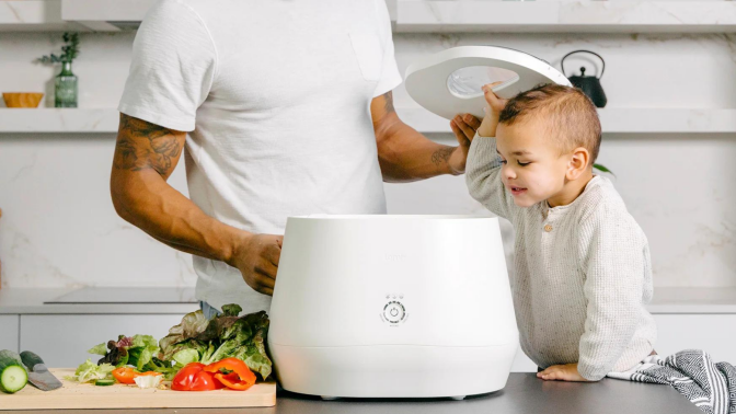 Child and parent adding food to Lomi countertop composter in kitchen