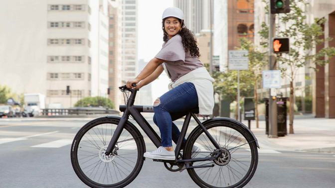 woman riding bird bike through city streets