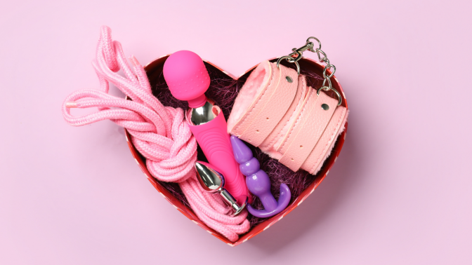 Box with toys from sex shop on color background