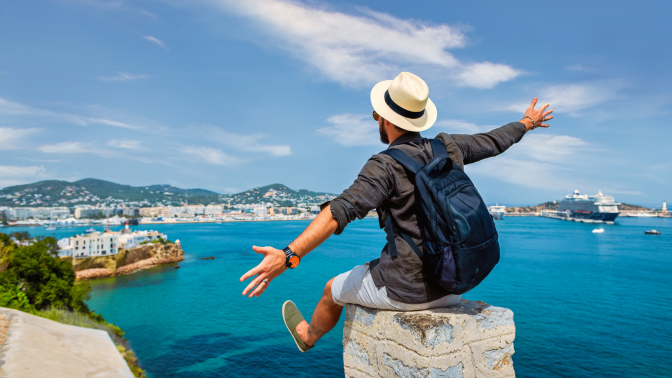 man with his hands in the air looking at the sea