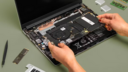 a close-up of a person assembling a framework laptop 13 against a green background