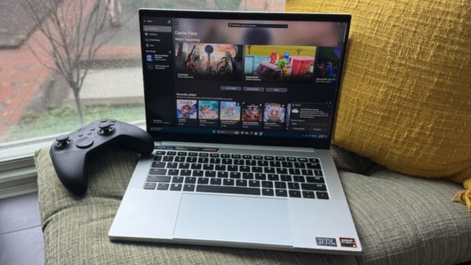 a razer blade 14 sitting on a windowsill cushion next to a gaming controller