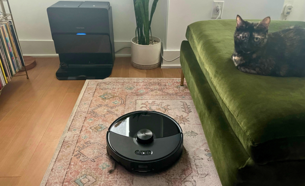 Roborock S8 MaxV Ultra robot vacuum cleaning rug with dock, green couch, and cat in peripherals