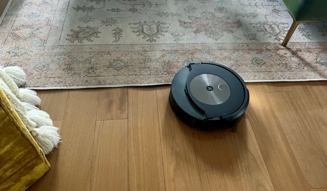 Roomba mopping hardwood floor with yellow chair and rug in background